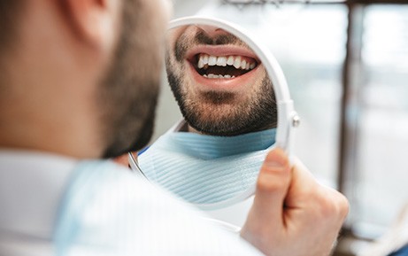 Patient smiling at reflection in handheld mirror