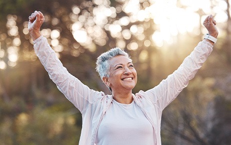 Woman outside smiling with arms outstretched victoriously