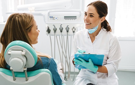 Dentist smiling while taking notes on clipboard