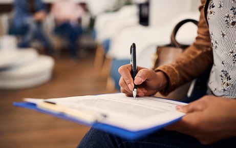 Patient filling out paperwork on clipboard in lobby