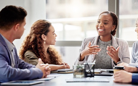 Four people discussing project with folder at meeting table