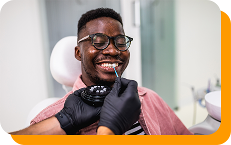 Man smiling while dentist holds veneer to his teeth
