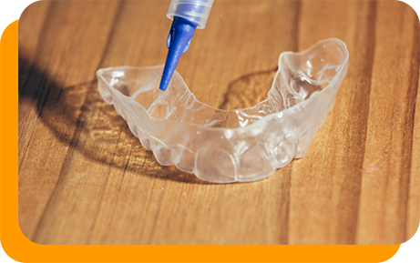 Applicator putting bleaching gel into a teeth whitening tray