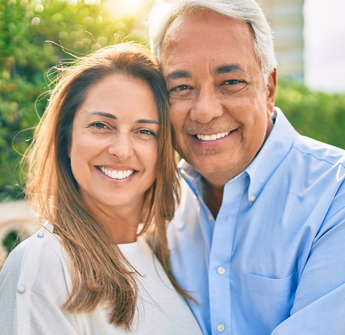 Older man and woman outdoors smiling with dental implants in Clearwater