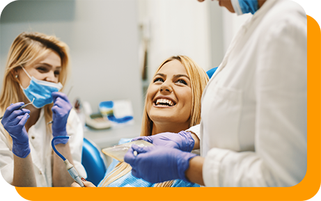 Woman in dental chair grinning up at her dentist
