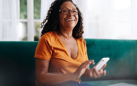 Woman with glasses smiling while holding phone