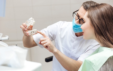 Dentist showing sample replacement teeth to patient 