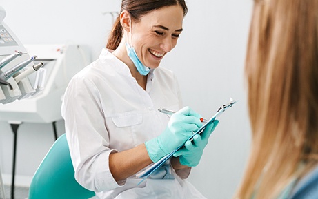 Smiling dentist taking notes on clipboard