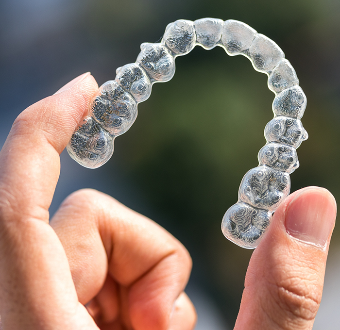 Hand holding an Invisalign clear aligner in Clearwater