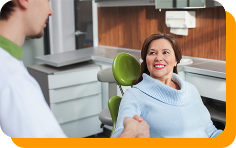 Woman in dental chair smiling while listening to her dentist