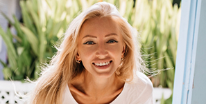 Blonde woman smiling with green plants in background
