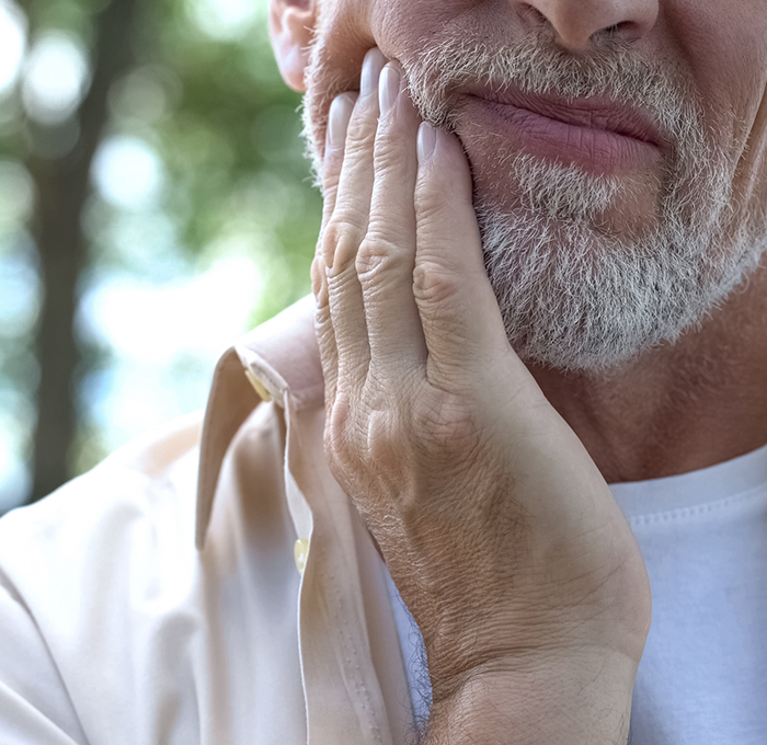 Man holding the side of his jaw in pain before root canal treatment in Clearwater