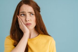 Woman holding jaw frowning. 
